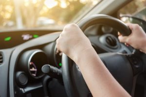 A driver's hands on a steering wheel.