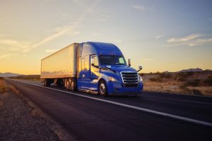 A large tractor-trailer on a highway under an open sky.