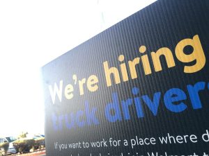 A sign advertises: "We're hiring truck drivers."