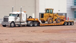 Parked semi-truck equipped with drop bed trailer ready to transport pay loader