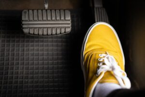 Driver pressing gas pedal of vehicle wearing yellow sneakers